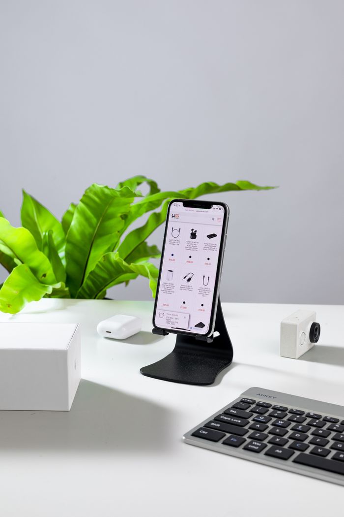 Services A smartphone on a stand with a keyboard and accessories on a white desk.