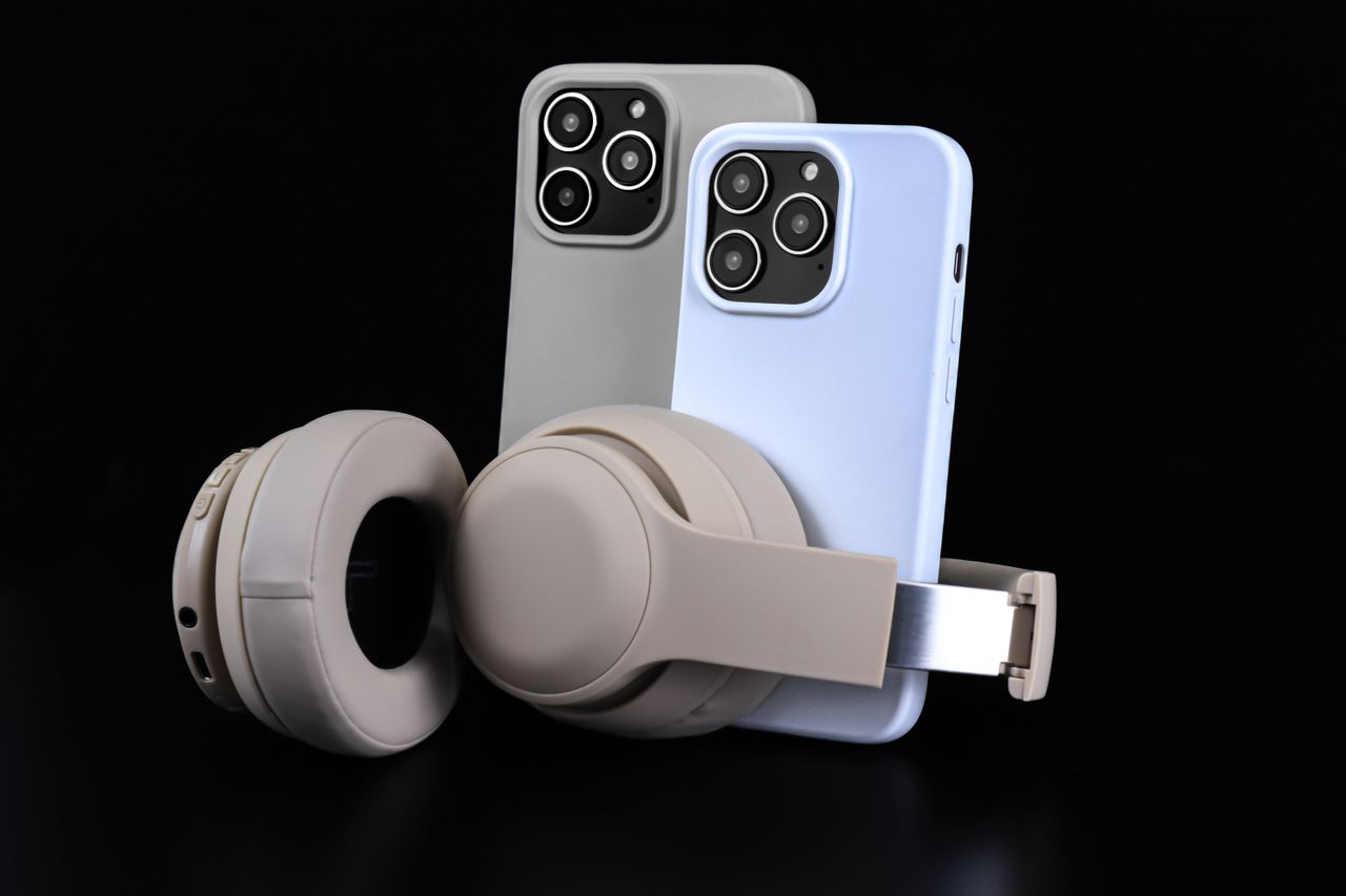 Services Pair of smartphones with beige headphones on black background, showcasing modern technology.
